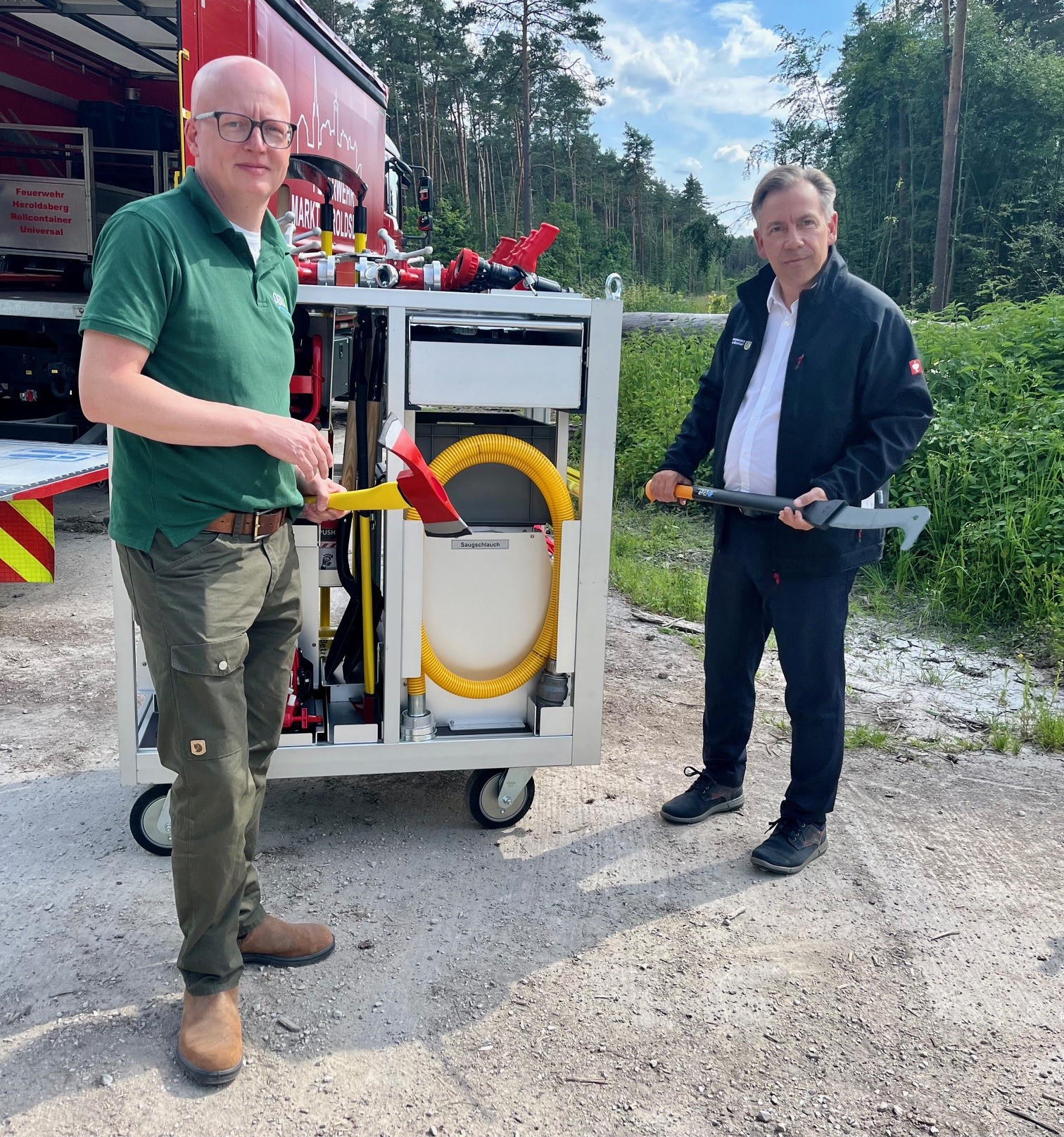 Landrat Tritthart (r.) und Christian Sürie vom DBU Naturerbe begutachten das Regnersystem, das der Feuerwehr Heroldsberg übergeben wurde